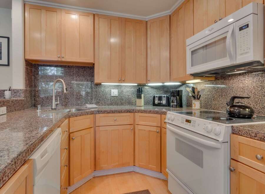 This charming kitchen features light wood cabinetry and a speckled granite countertop, offering a warm and inviting atmosphere.