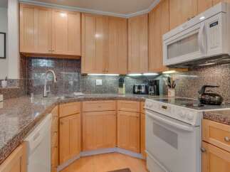 This charming kitchen features light wood cabinetry and a speckled granite countertop, offering a warm and inviting atmosphere.