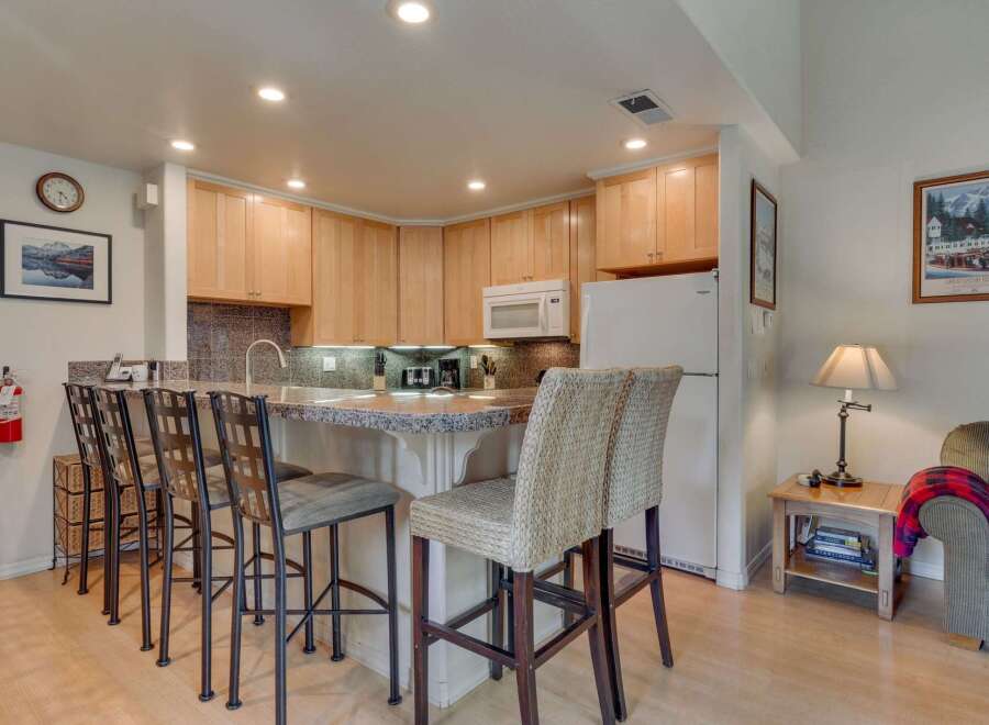 This charming kitchen features light wood cabinetry and a granite-topped island with bar seating, perfect for casual dining.