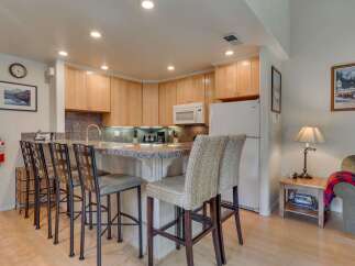 This charming kitchen features light wood cabinetry and a granite-topped island with bar seating, perfect for casual dining.