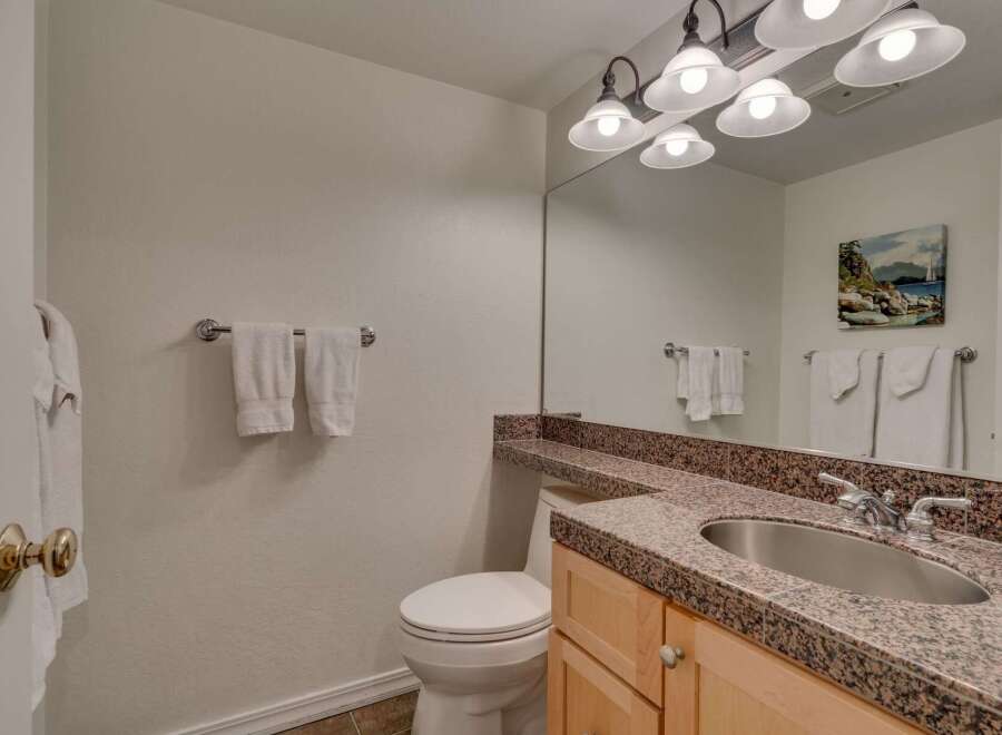 This bathroom features a clean and functional design with a white toilet and a vanity with a granite countertop.