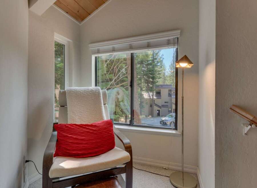 Relax and unwind in this cozy reading nook, complete with a comfortable chair and a plush red accent pillow.