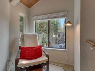 Relax and unwind in this cozy reading nook, complete with a comfortable chair and a plush red accent pillow.