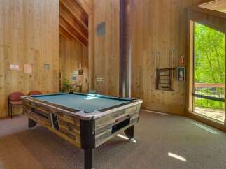 Enjoy a game of pool in this spacious recreation room, featuring a full-sized pool table and ample natural light.