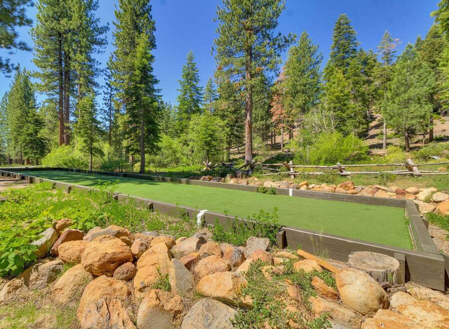 Enjoy outdoor recreation with this beautifully maintained bocce ball court, nestled amidst a serene forest setting.
