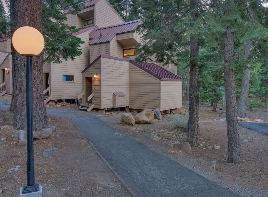 Nestled amidst tall pine trees, this charming property features a unique multi-level design with a distinctive copper-colored roof.