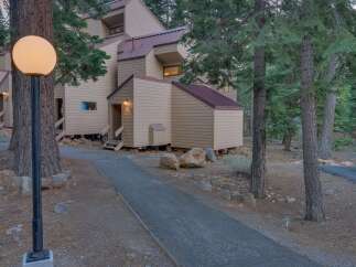 Nestled amidst tall pine trees, this charming property features a unique multi-level design with a distinctive copper-colored roof.