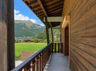 Experience breathtaking mountain views from this charming wooden chalet's covered balcony.