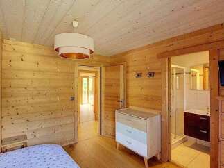 Experience rustic charm in this beautifully appointed bedroom featuring warm, natural wood paneling throughout the walls and ceiling.