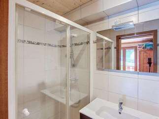 This charming bathroom features a spacious glass-enclosed shower with tiled walls and a built-in bench.