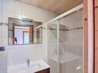 This charming bathroom features a modern vanity with ample storage and a sleek sink, complemented by a spacious glass-enclosed shower.