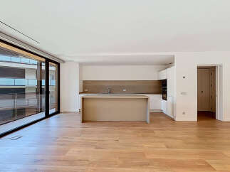 Experience modern living in this spacious open-plan apartment featuring a sleek, contemporary kitchen with an island and integrated appliances.