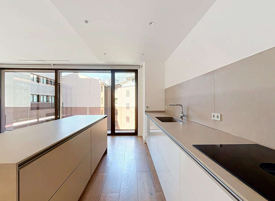 Experience modern living in this sleek kitchen featuring a spacious island and a seamless countertop with an integrated sink and faucet.
