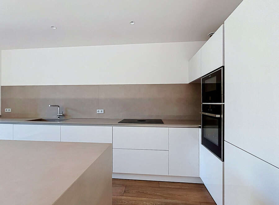 Experience modern living in this sleek, minimalist kitchen featuring integrated appliances and ample counter space.