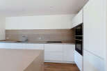Experience modern living in this sleek, minimalist kitchen featuring integrated appliances and ample counter space.