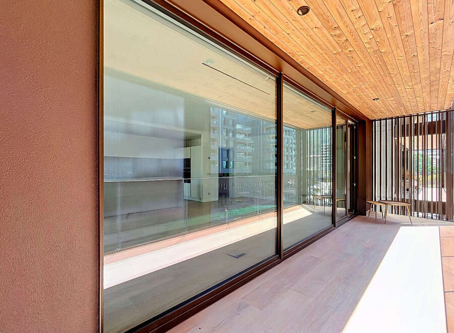 Experience luxurious indoor-outdoor living with expansive floor-to-ceiling glass doors that open onto a spacious balcony.
