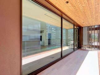 Experience luxurious indoor-outdoor living with expansive floor-to-ceiling glass doors that open onto a spacious balcony.