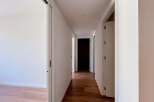 Step into this bright and airy hallway, featuring a sleek sliding door on the left and a passage leading to multiple rooms.