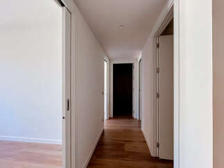Step into this bright and airy hallway, featuring a sleek sliding door on the left and a passage leading to multiple rooms.