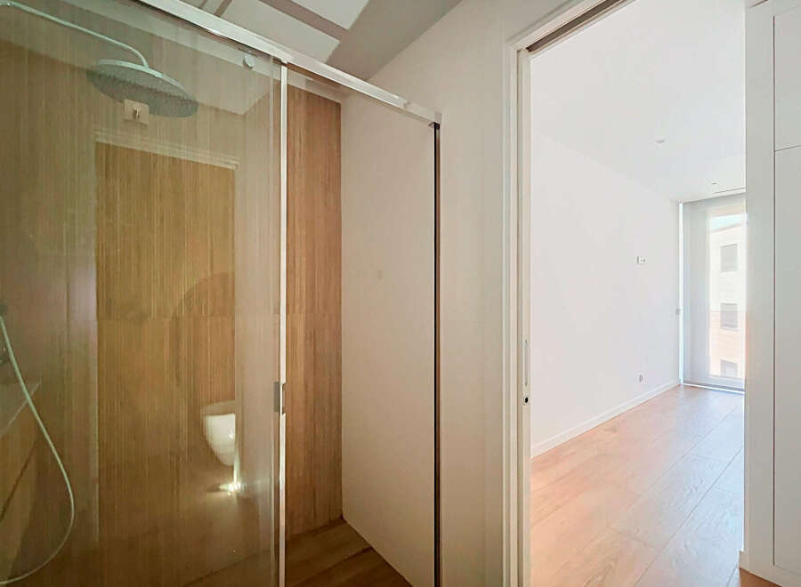 Step into a modern bathroom featuring a sleek glass-enclosed shower with a rainfall showerhead and elegant wood-paneled walls.