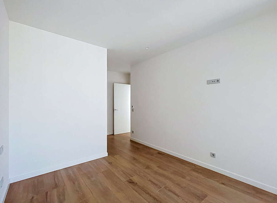 Discover this bright and airy room featuring pristine white walls and a beautiful wooden floor.