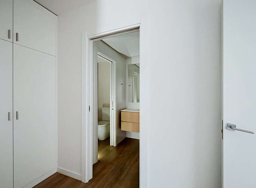 Step into a modern and bright living space featuring sleek white cabinetry and a convenient doorway leading to a well-appointed bathroom.