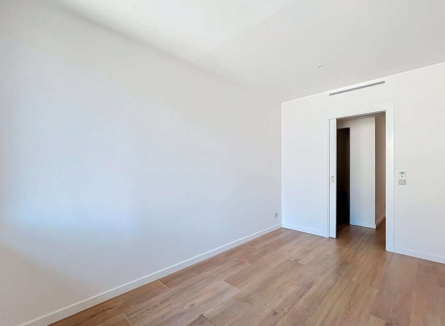 Step into this bright and airy room, featuring pristine white walls and elegant wooden flooring that exudes warmth and sophistication.