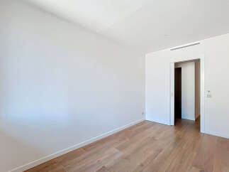Step into this bright and airy room, featuring pristine white walls and elegant wooden flooring that exudes warmth and sophistication.