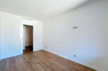 This spacious room features a clean, modern aesthetic with white walls and a sleek air vent.