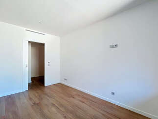 This spacious room features a clean, modern aesthetic with white walls and a sleek air vent.