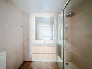 This modern bathroom features a sleek vanity with ample storage, a spacious walk-in shower with a rainfall showerhead, and a large vanity mirror.