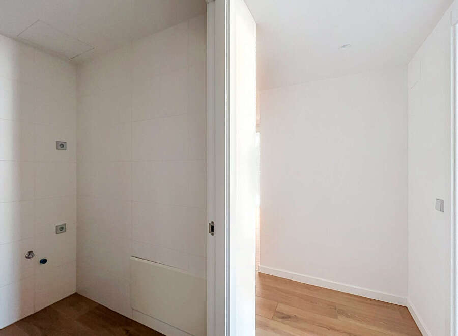 Discover this bright and airy space, featuring clean white tiled walls and a modern wooden floor.