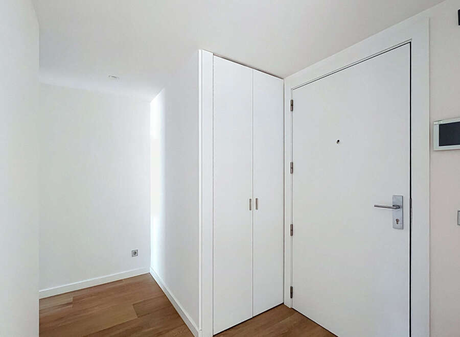 Step into this modern and bright entryway, featuring a sleek white door with a brushed nickel handle and a discreet peephole.