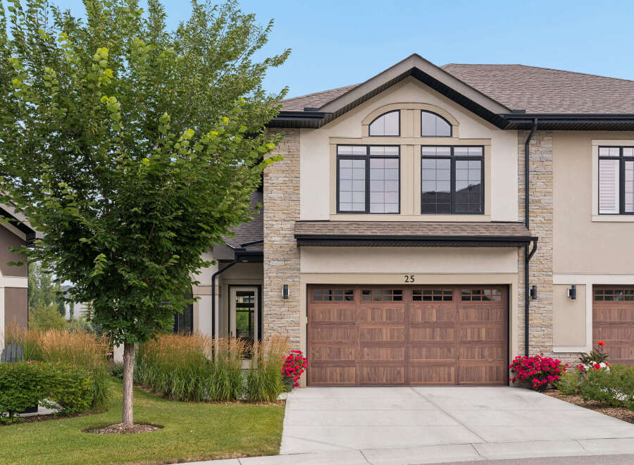 This stunning townhouse features a modern facade with stone accents and a prominent arched window above the main living area.