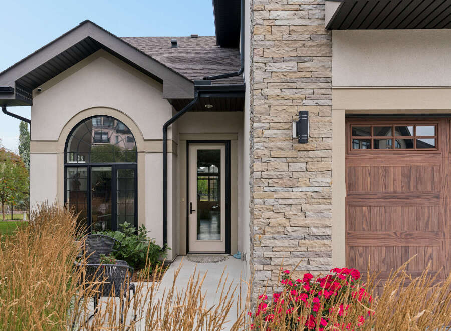 This stunning home features a beautiful arched window and a welcoming front door, perfect for greeting guests.