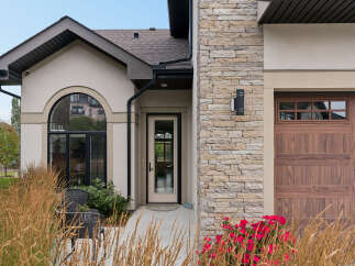 This stunning home features a beautiful arched window and a welcoming front door, perfect for greeting guests.
