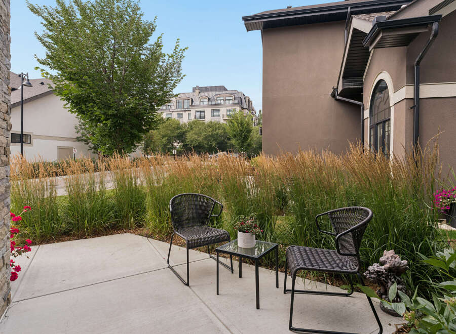 Enjoy your morning coffee on this charming patio, complete with two comfortable wicker chairs and a glass-top table.