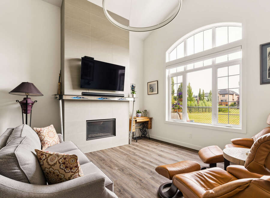 Experience modern living in this spacious living room, featuring a sleek fireplace and a large, arched window that floods the space with natural light.