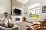 Experience modern living in this spacious living room, featuring a sleek fireplace and a large, arched window that floods the space with natural light.