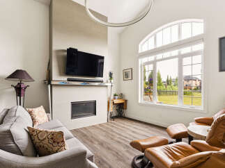 Experience modern living in this spacious living room, featuring a sleek fireplace and a large, arched window that floods the space with natural light.