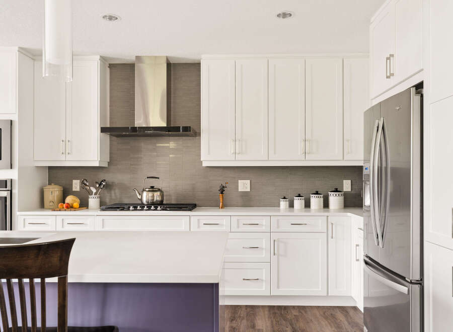 Experience modern living in this stunning kitchen, featuring sleek white cabinetry, a stylish stainless steel range hood, and a durable quartz countertop.