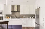 Experience modern living in this stunning kitchen, featuring sleek white cabinetry, a stylish stainless steel range hood, and a durable quartz countertop.