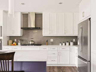 Experience modern living in this stunning kitchen, featuring sleek white cabinetry, a stylish stainless steel range hood, and a durable quartz countertop.