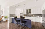 Experience modern living in this stunning kitchen featuring sleek white cabinetry, a spacious island with a purple base, and a sophisticated grey tiled backsplash.