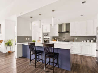 Experience modern living in this stunning kitchen featuring sleek white cabinetry, a spacious island with a purple base, and a sophisticated grey tiled backsplash.