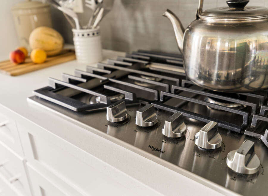 Experience culinary excellence in this modern kitchen, featuring a sleek stainless steel gas range with precise temperature control knobs.