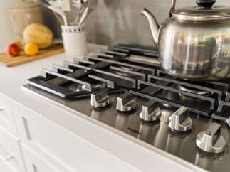 Experience culinary excellence in this modern kitchen, featuring a sleek stainless steel gas range with precise temperature control knobs.