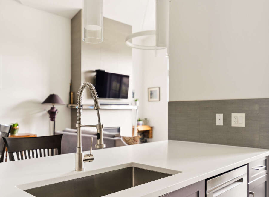 Experience modern living in this stunning kitchen featuring a sleek stainless steel sink and a contemporary faucet.