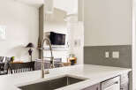 Experience modern living in this stunning kitchen featuring a sleek stainless steel sink and a contemporary faucet.