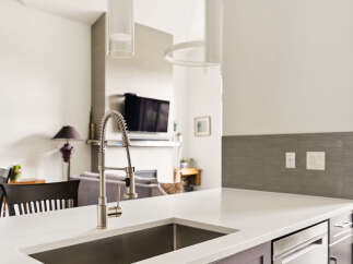 Experience modern living in this stunning kitchen featuring a sleek stainless steel sink and a contemporary faucet.